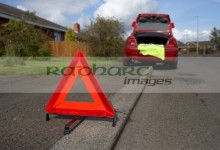 hazard warning triangle laid out on the side of the road in a residential area behind a broken down car