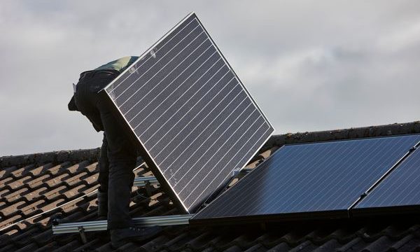 man installing rooftop solar panel array in a domestic solar panel installation in the uk