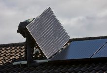 man installing rooftop solar panel array in a domestic solar panel installation in the uk